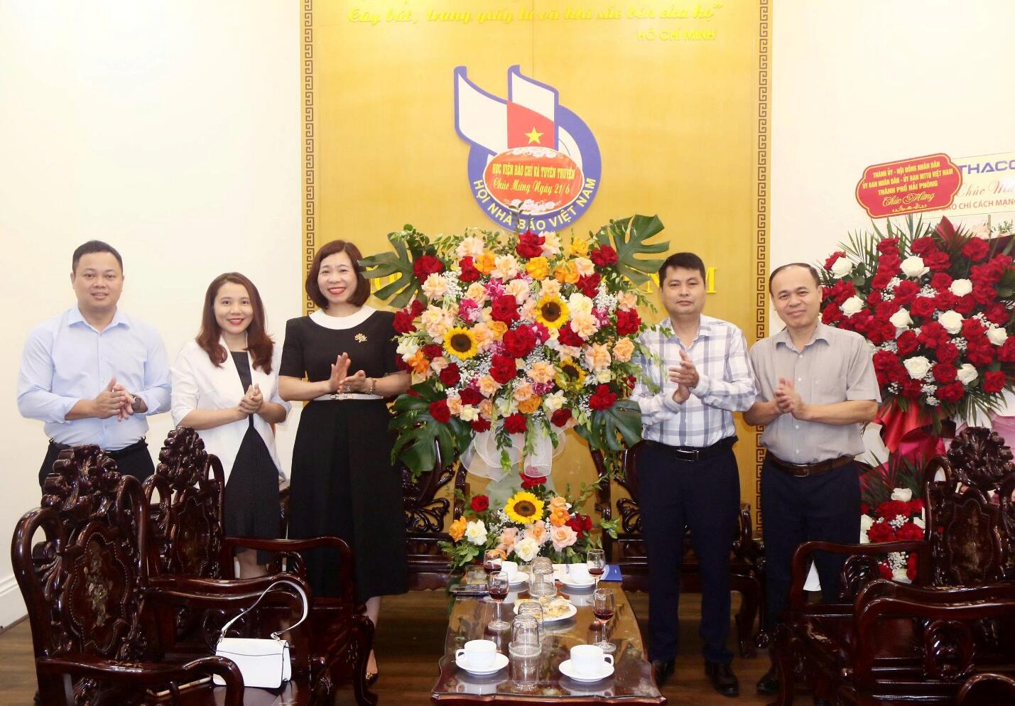 A group of people standing in front of a large flower arrangement Description automatically generated