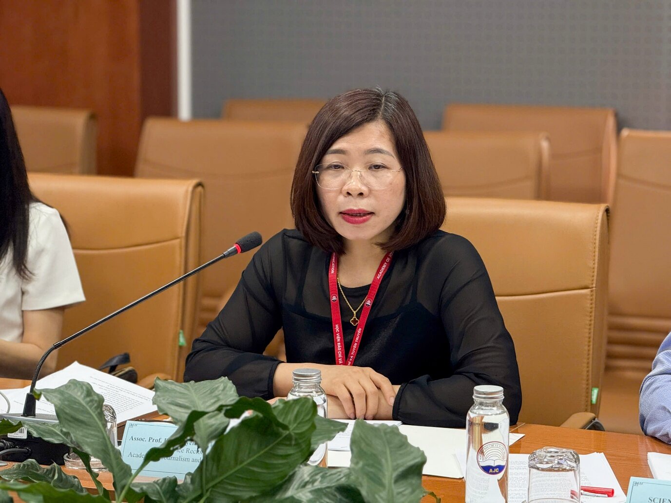 A person sitting at a table with a microphone Description automatically generated