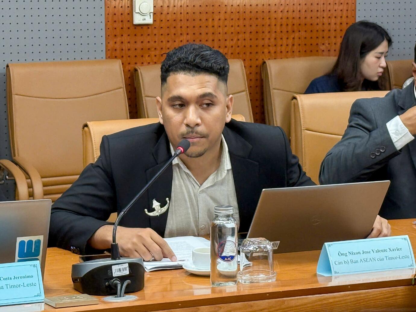 A person sitting at a table with a microphone Description automatically generated