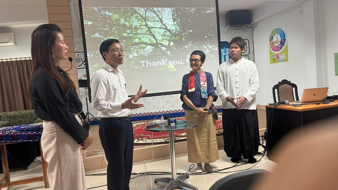 A group of people standing in front of a projection screen Description automatically generated