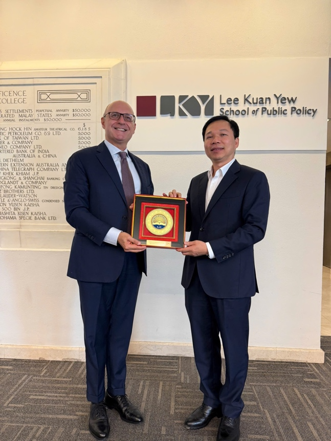 Two men in suits holding a plaque Description automatically generated