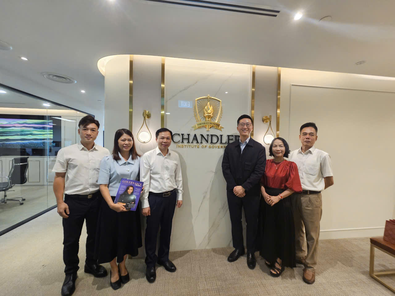 A group of people standing in front of a sign Description automatically generated