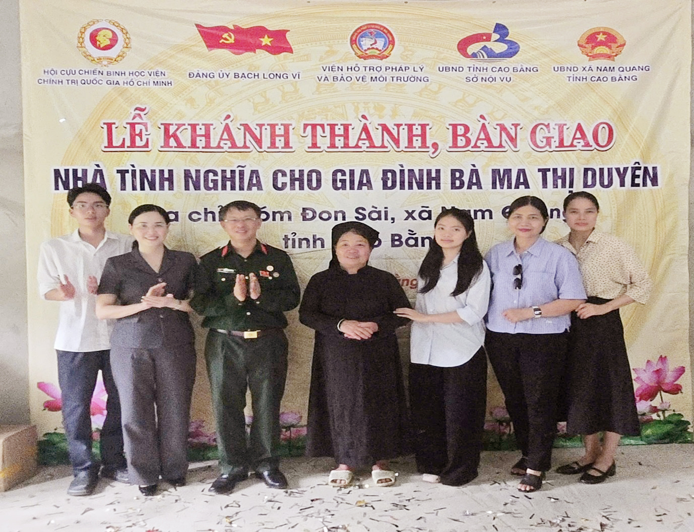 A group of people standing in front of a banner Description automatically generated