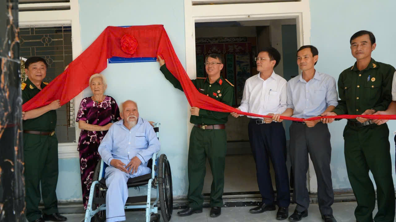 A group of people holding a red ribbon Description automatically generated