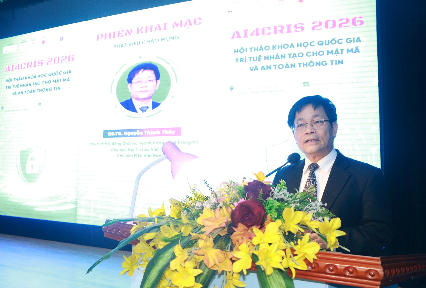 A person standing at a podium with a microphone and flowers Description automatically generated